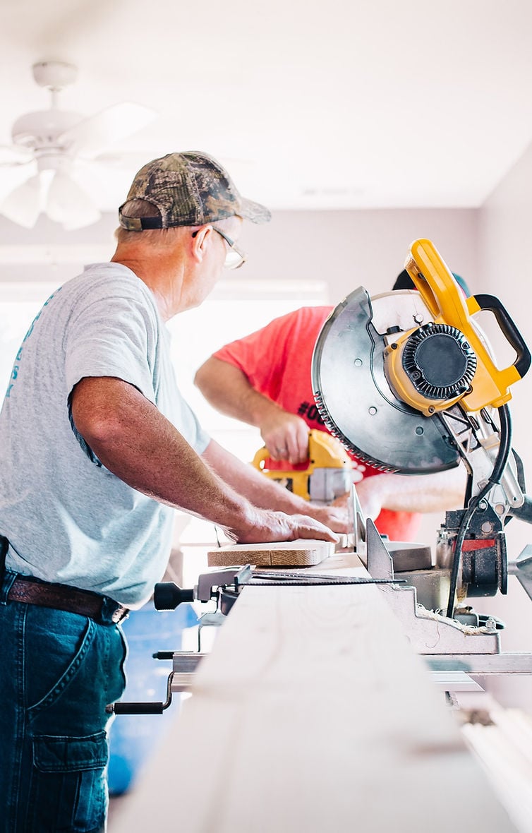 Two men using a mitre saw